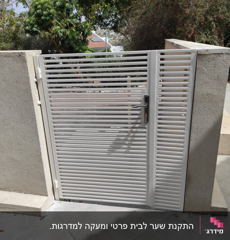 שער מתכת אפור עם ידית על קיר בטון